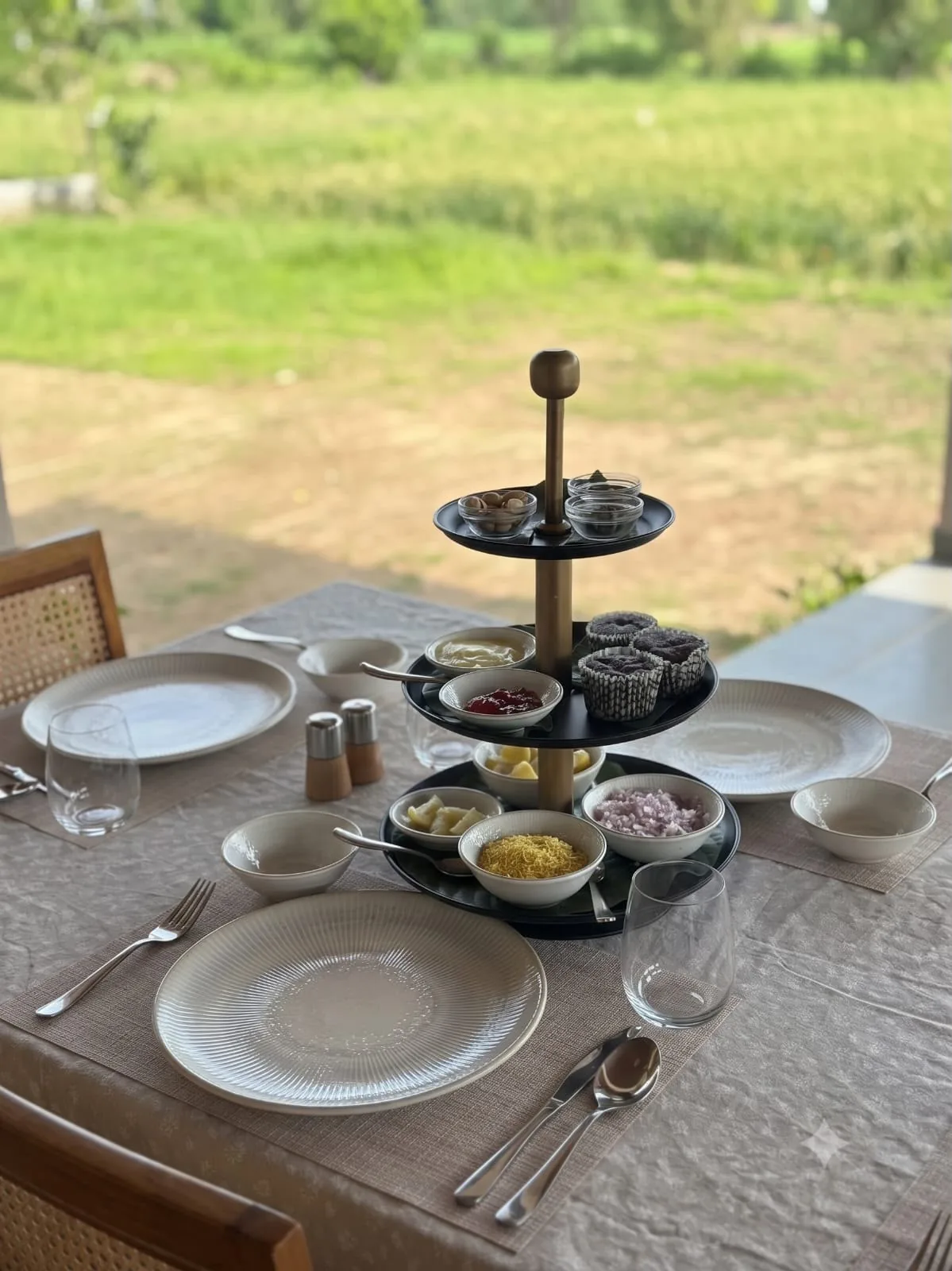 A tiered stand of snacks laid out on a table above green fields