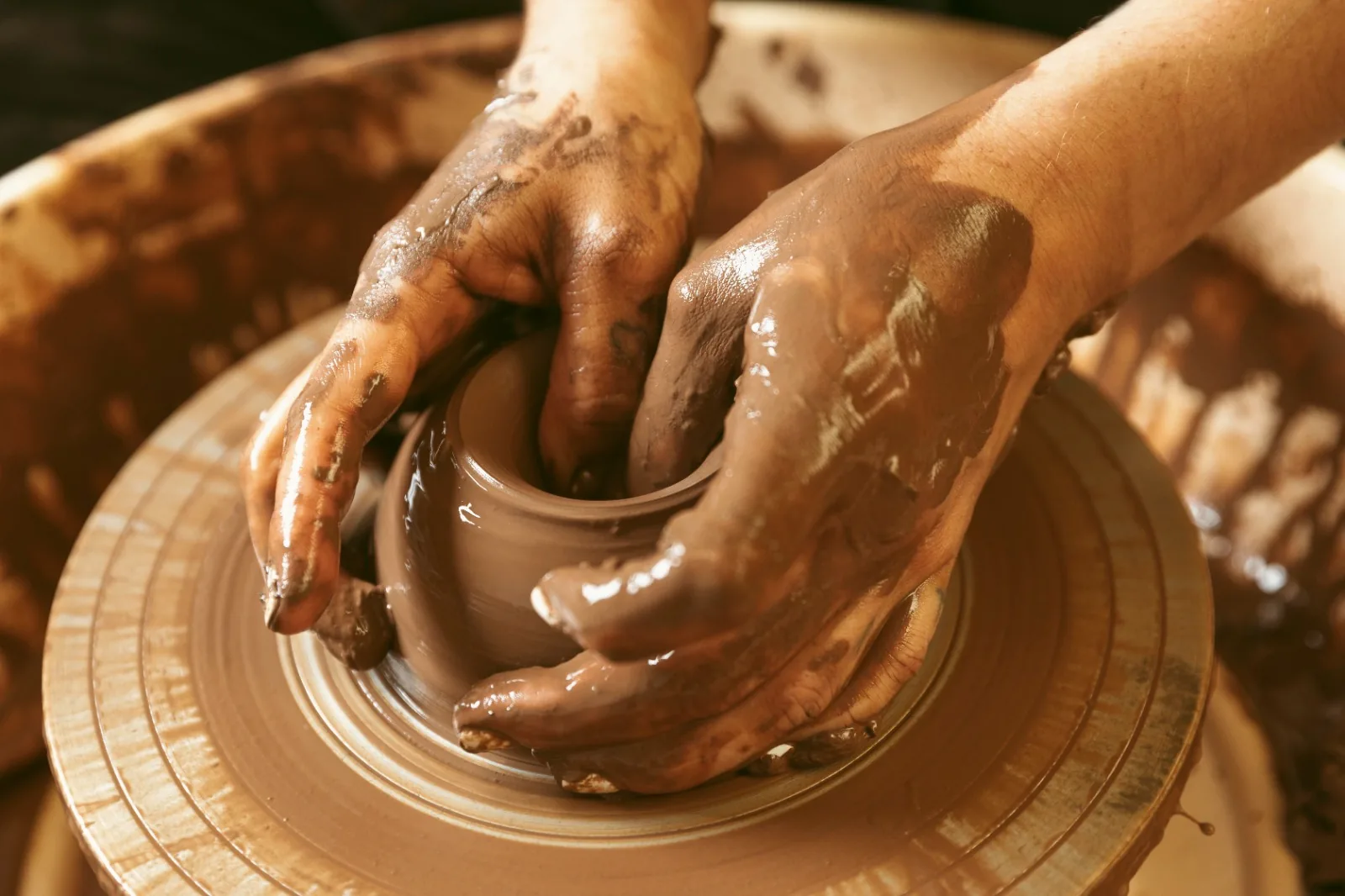 Hands shaping clay on a potters wheel
